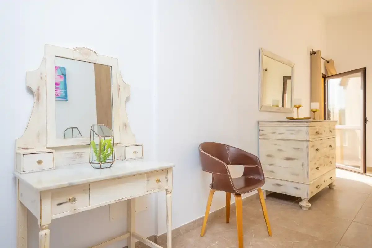 A bright room with a white vanity table and a brown chair.