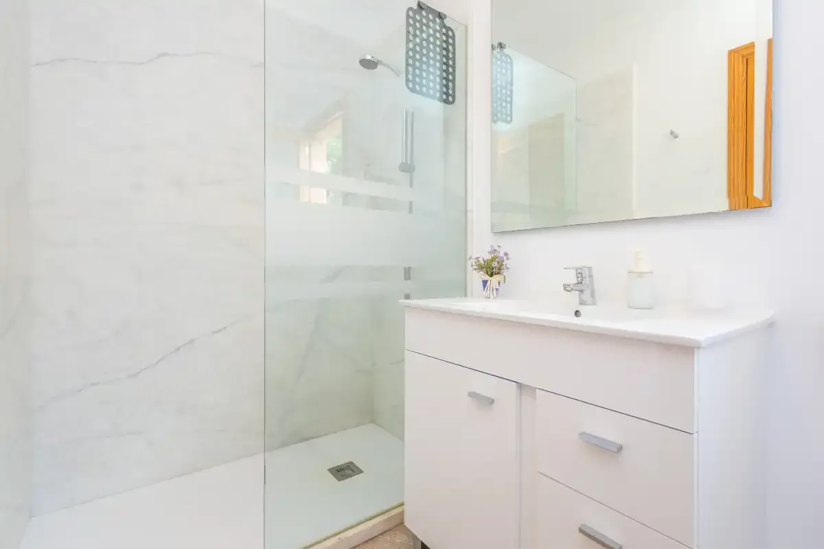 A bright bathroom with a glass shower and a white vanity.