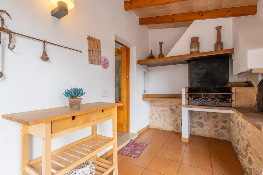 A rustic kitchen with a wooden worktable and a stone fireplace.