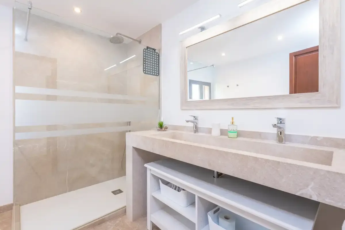 A bright bathroom with a wide vanity and glass shower.
