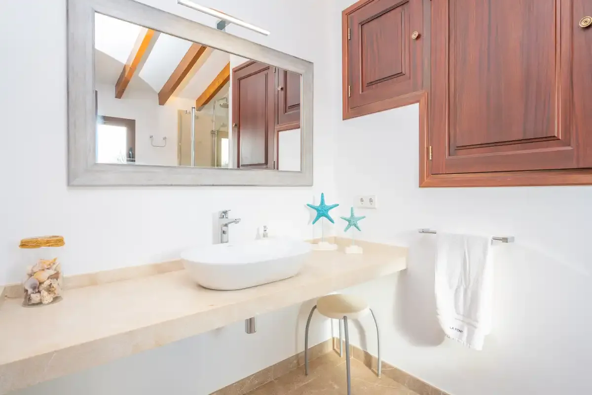 A bathroom vanity with a basin, mirror, and wooden cabinets.