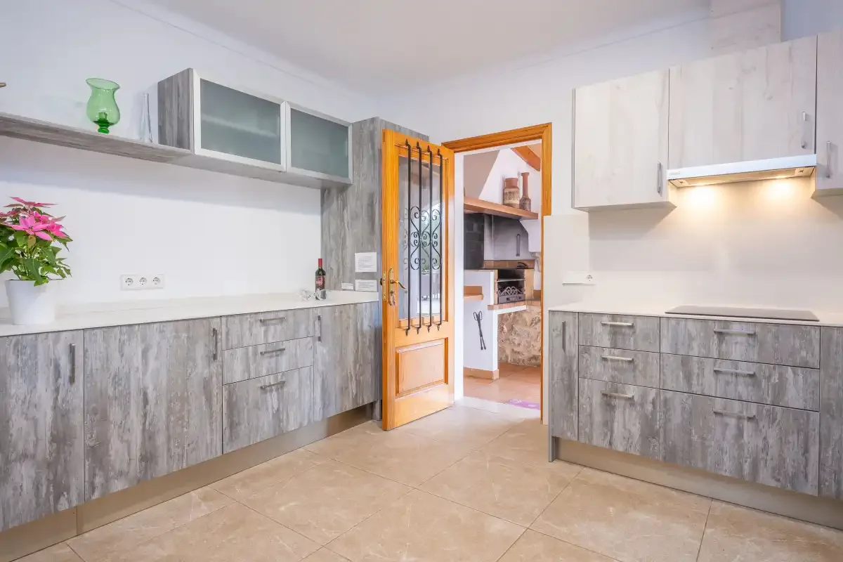 A bright kitchen with gray cabinets and an open wooden doorway.