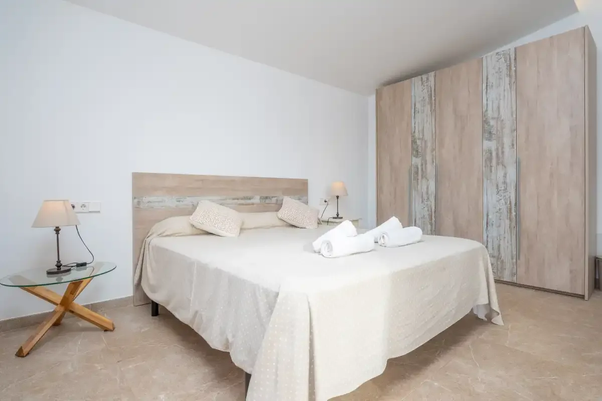 A bedroom with a neatly made bed and a large wardrobe.