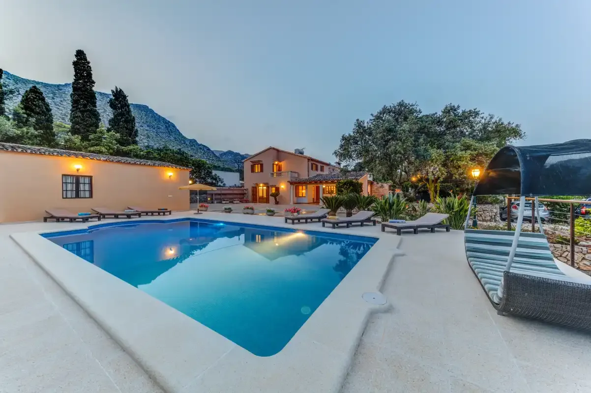 An outdoor swimming pool sits beside a house and patio seating.