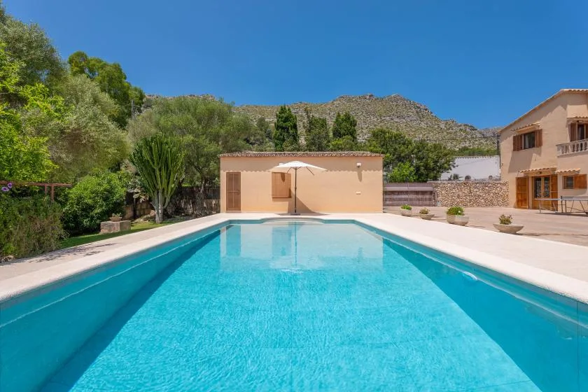 Una piscina ocupa el primer plano, con un patio y edificios al fondo.