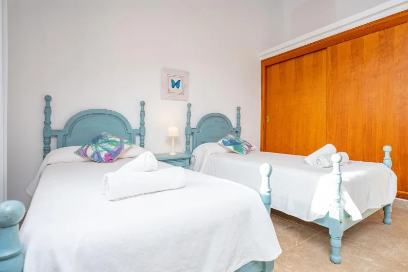 A bedroom with two beds, white bedding, and teal headboards.