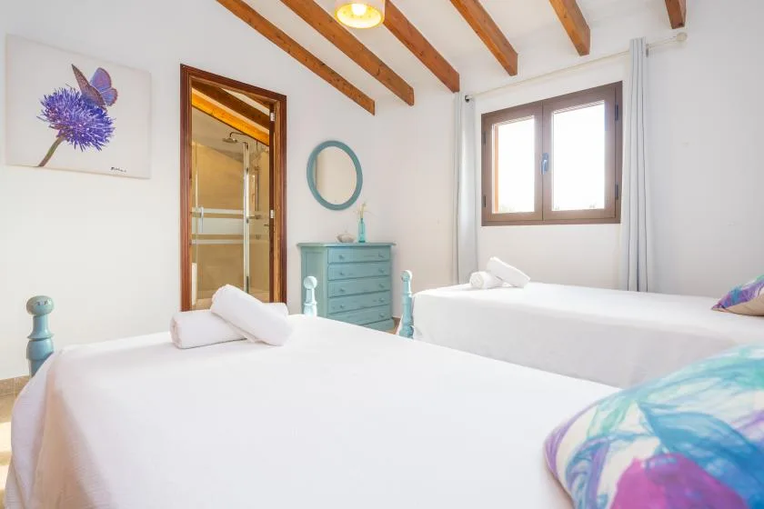 A bright bedroom with two beds and a window.