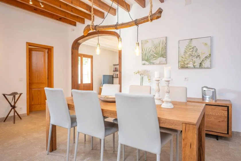 A dining room with a wooden table, light-colored seating, and framed botanical prints.