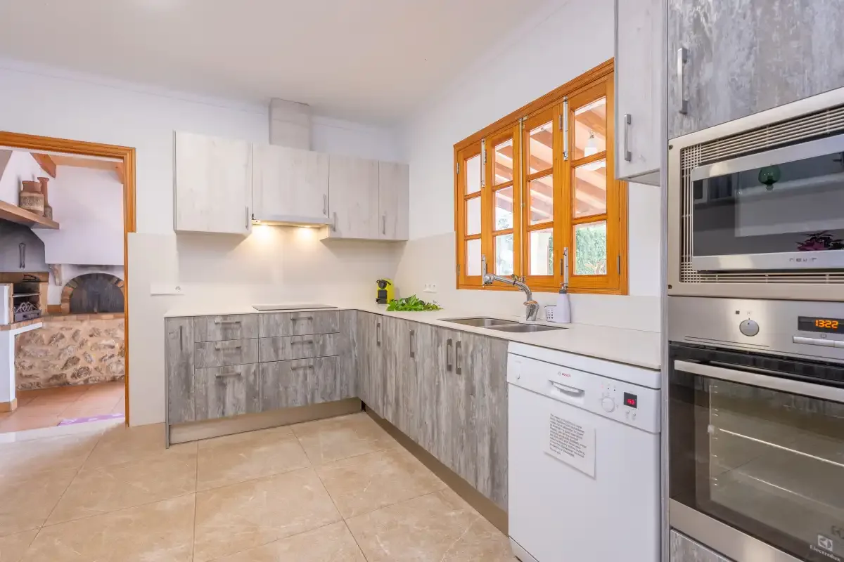 A bright kitchen with gray cabinets, a countertop, and orange-framed windows.