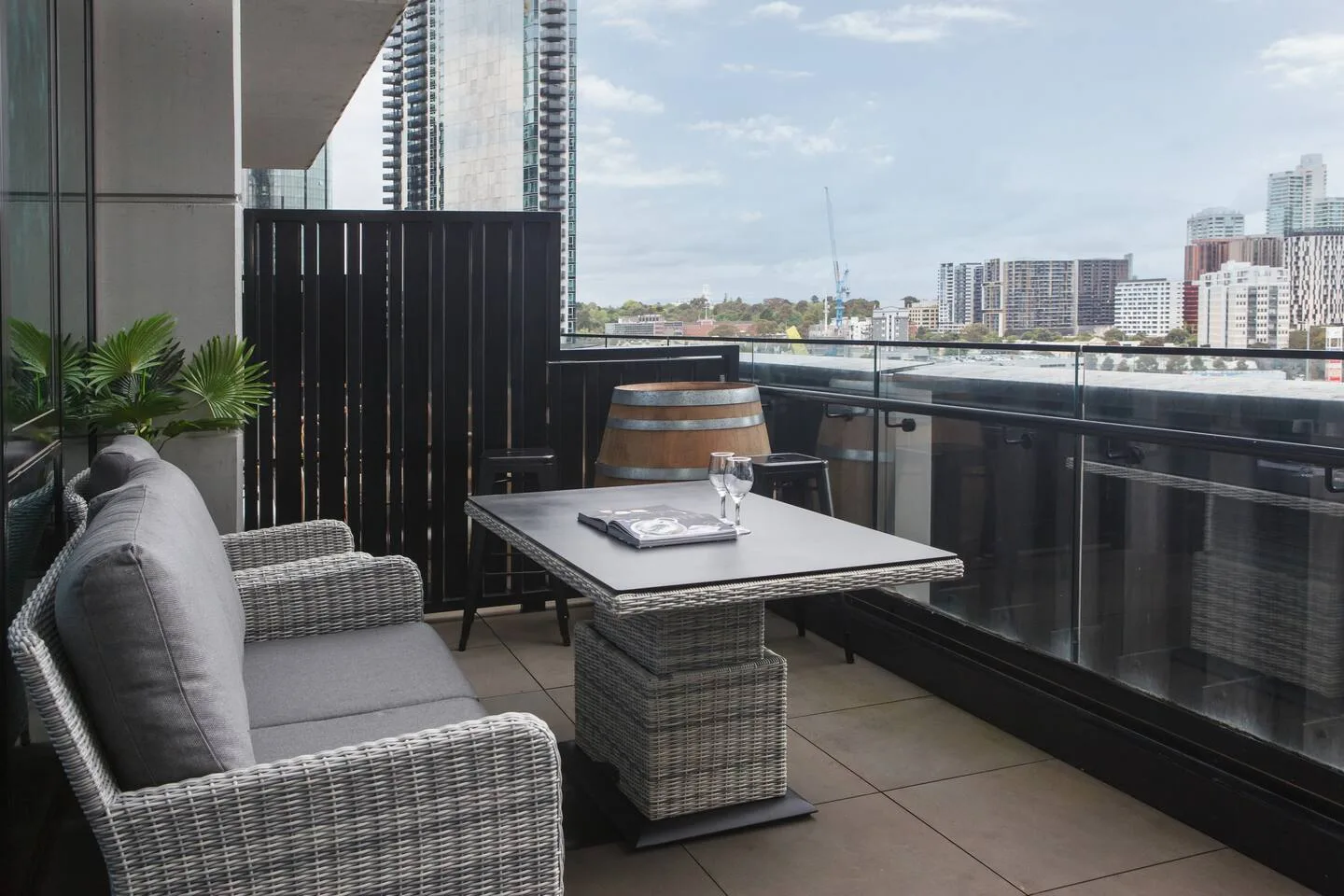 Un balcón amueblado tiene una zona de asientos y una mesa con vistas a la ciudad.