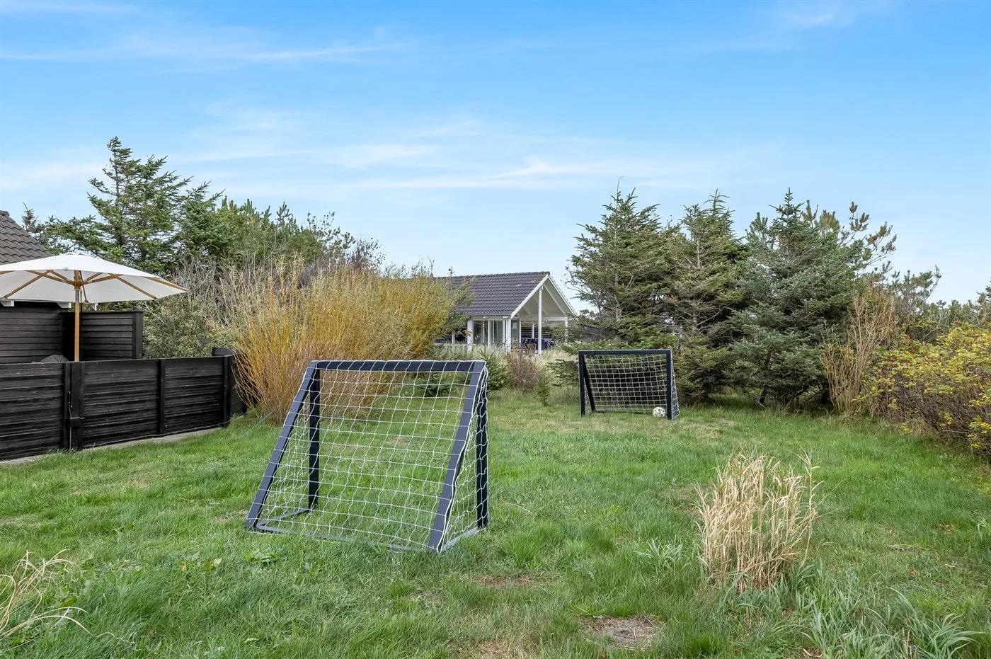 A grassy yard with two soccer goals and trees around the edges.