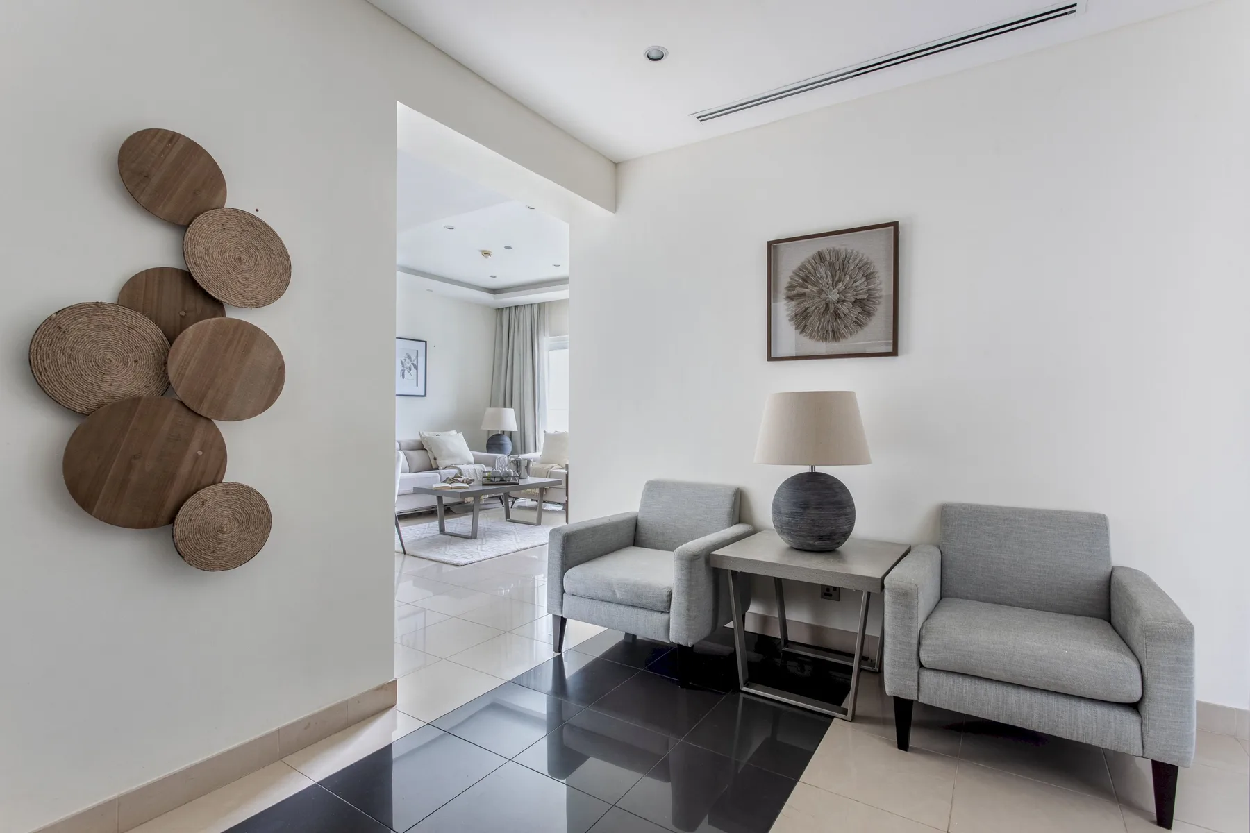 Una sala luminosa con dos sillones y una mesa pequeña.
