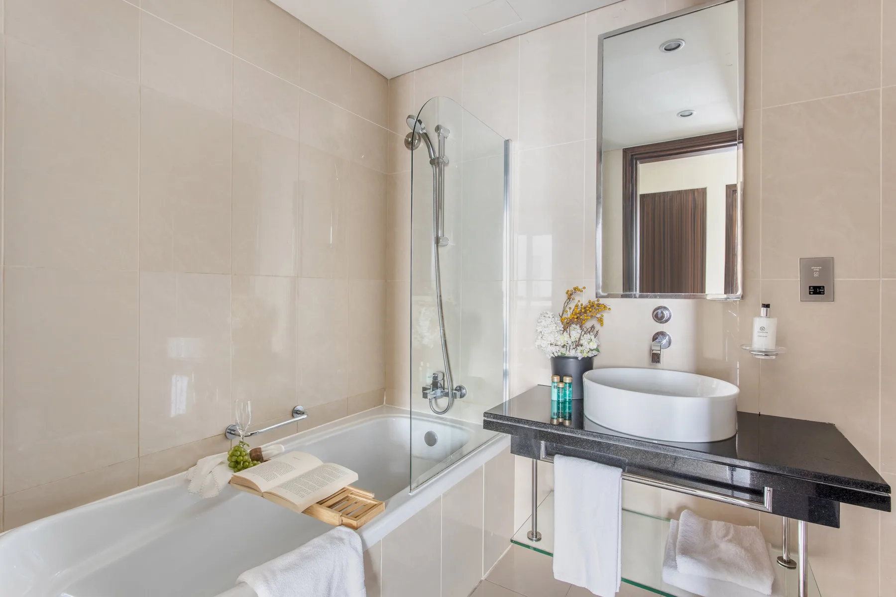 Un baño alicatado con bañera, mampara de ducha y lavabo.