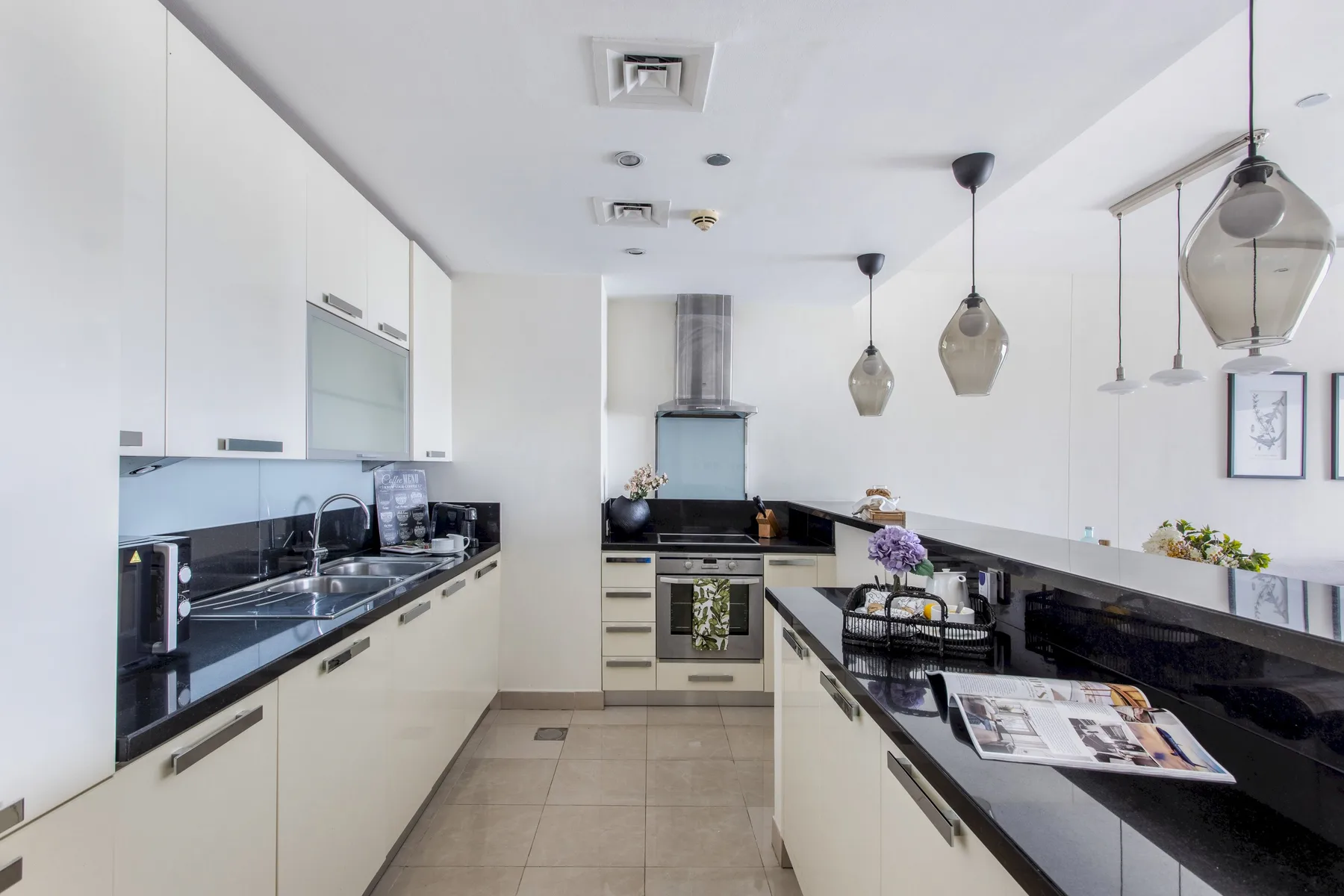 Una cocina moderna y luminosa con encimeras largas y lámparas colgantes.