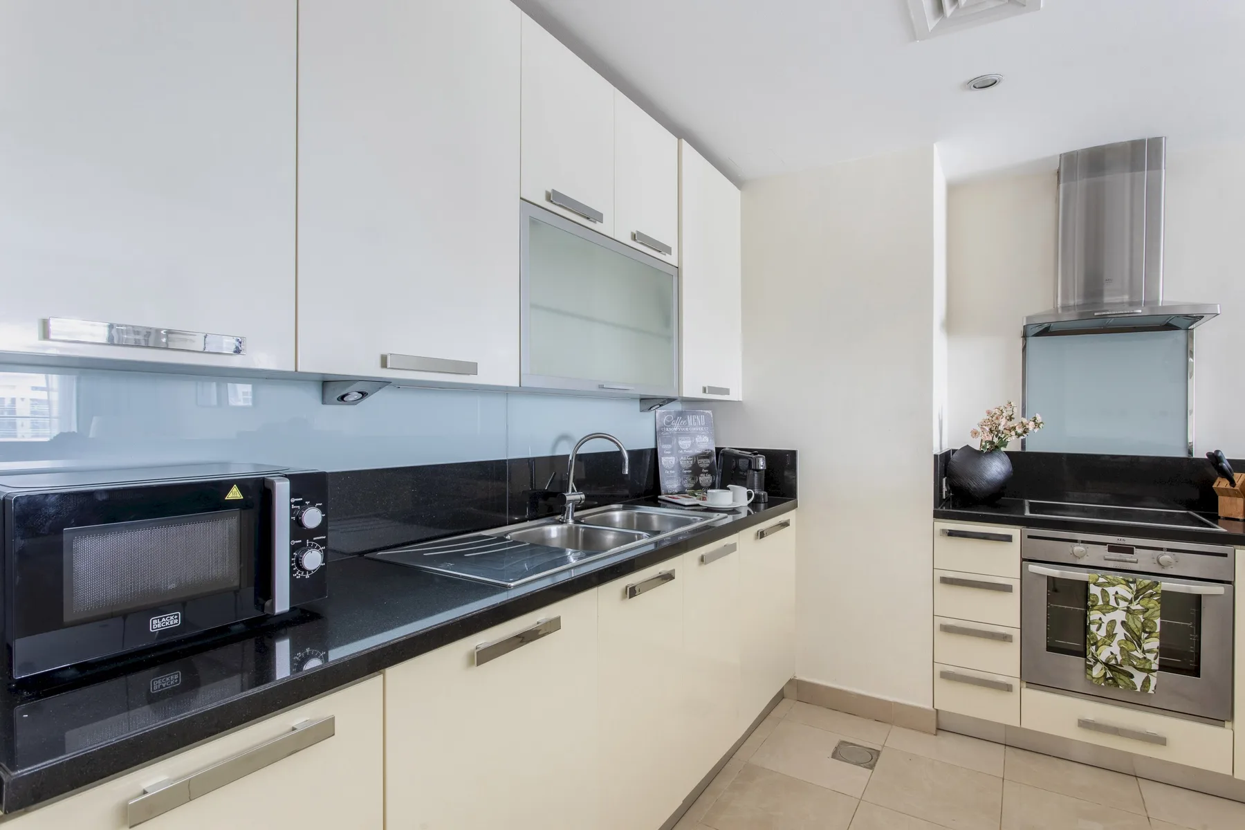 Una cocina moderna con encimeras negras, armarios blancos y electrodomésticos de acero inoxidable.