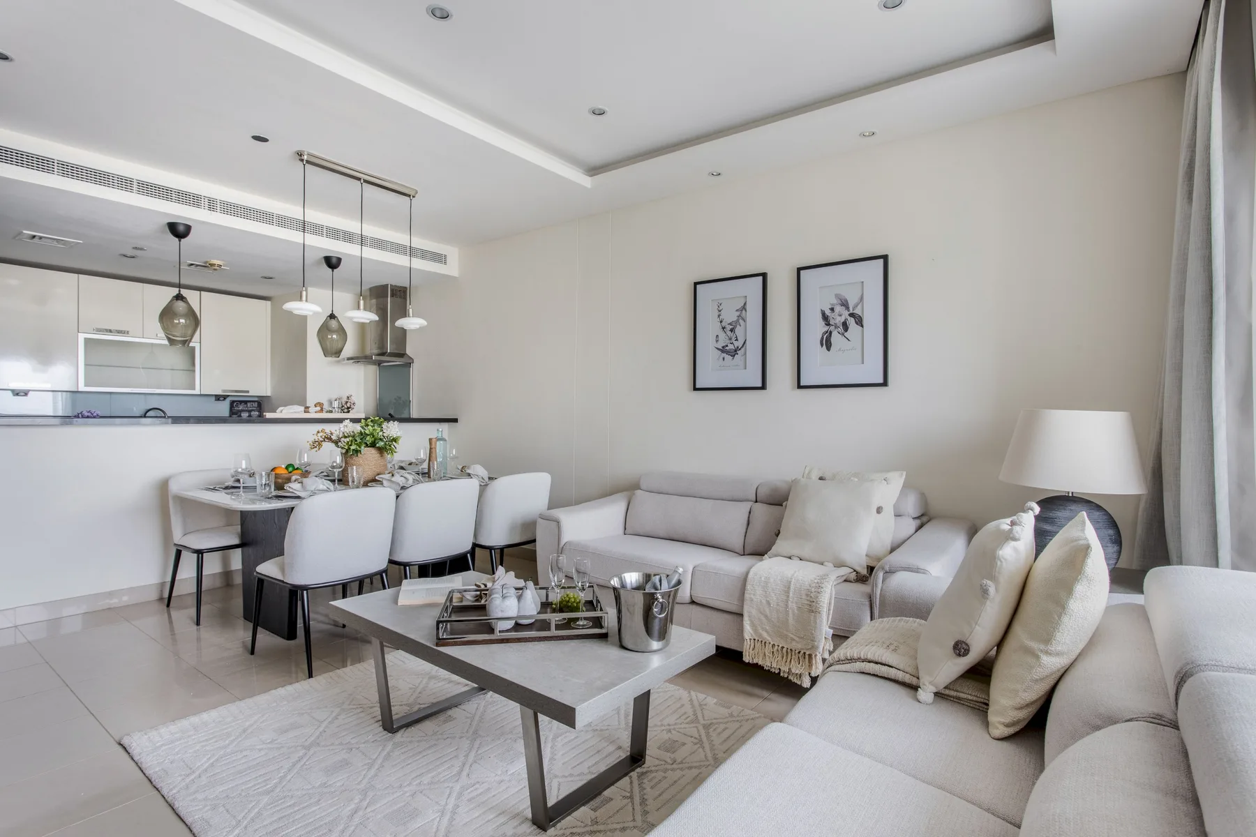 Una sala luminosa con una zona de asientos y una cocina abierta.
