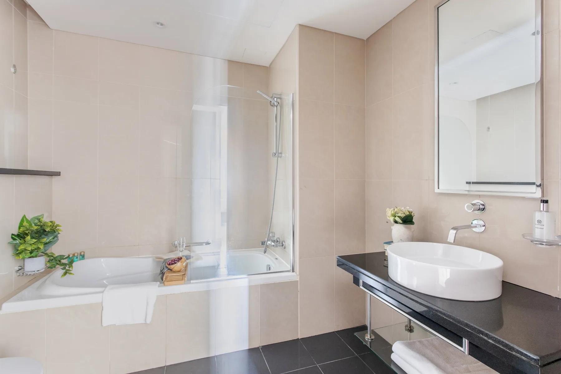 Un baño con azulejos, una bañera y un lavabo sobre la encimera.