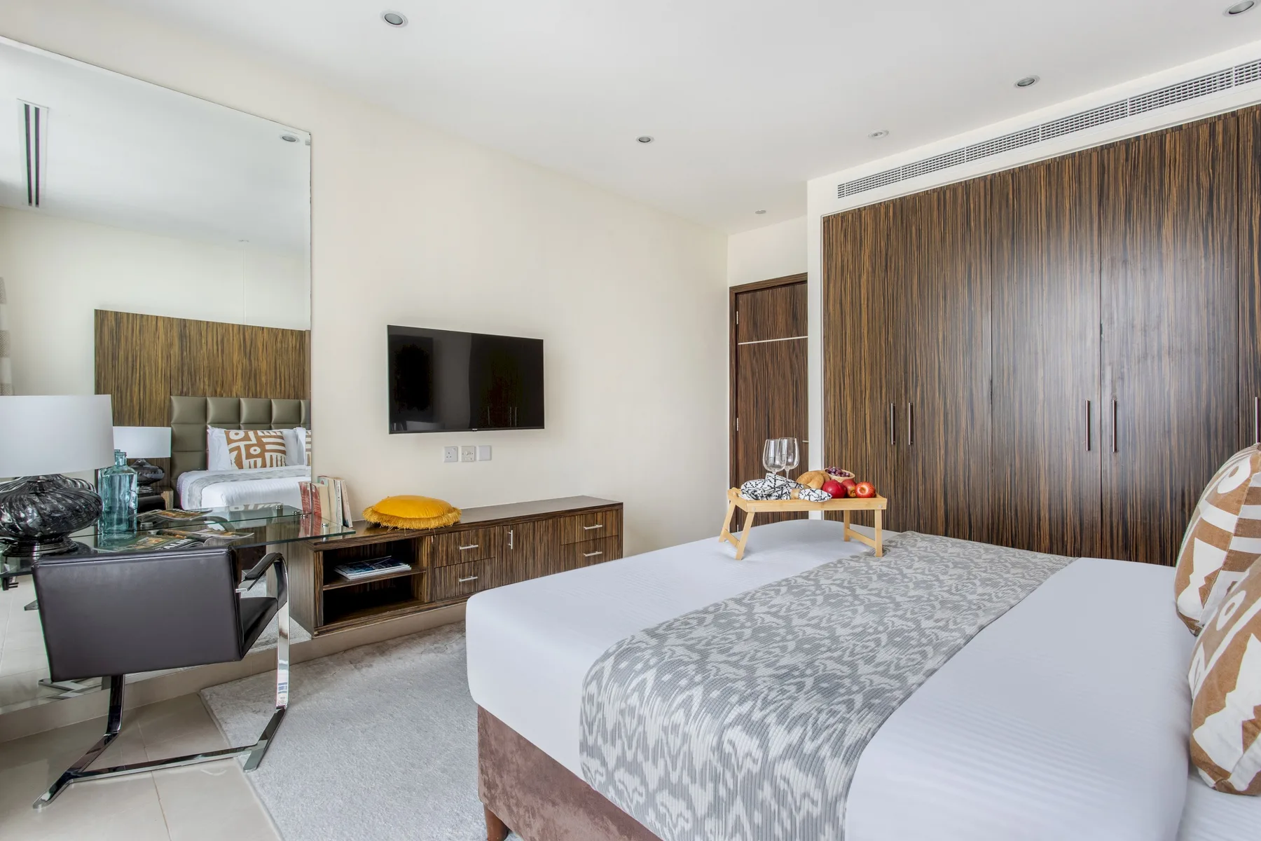 Un dormitorio con una cama, un televisor en la pared y un armario grande de madera.
