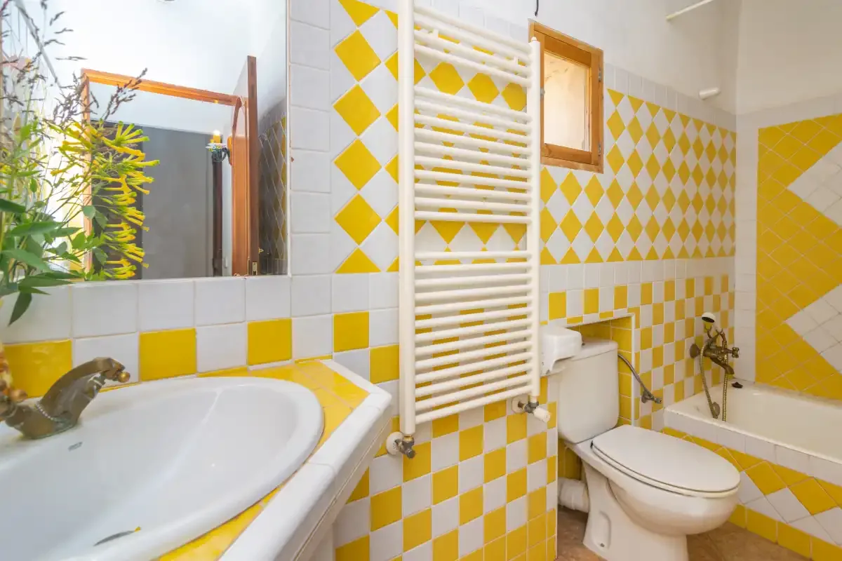 A bathroom with a sink, toilet, and bathtub, decorated with yellow-and-white tiles.