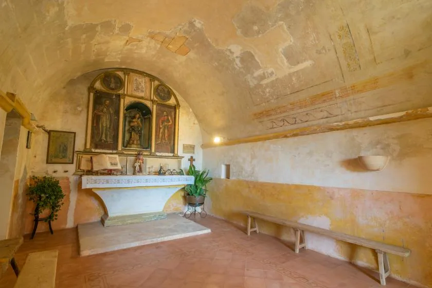 A small chapel with a decorated altar and a long bench along the wall.