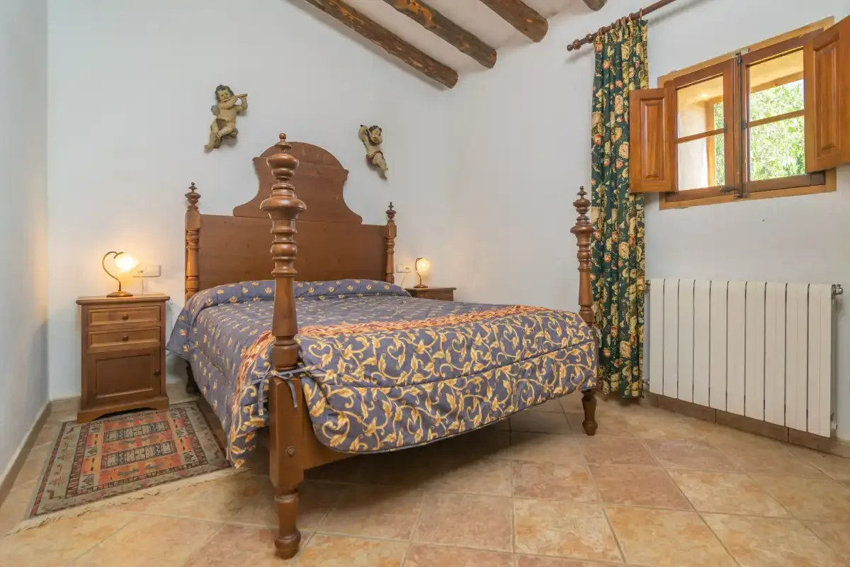A bedroom with a wooden bed, patterned bedding, and a window.