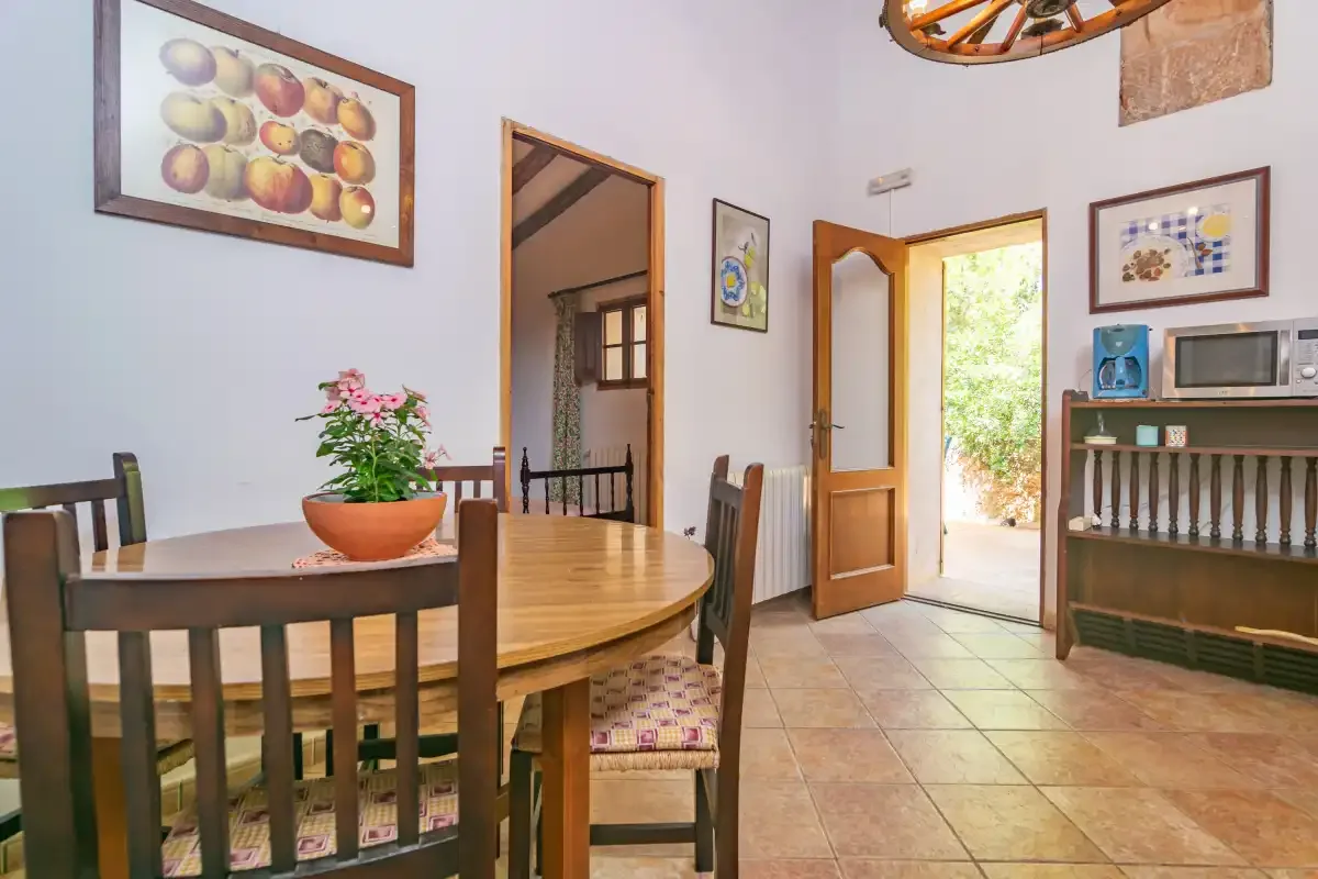 A dining area with a wooden table and an open door to the outdoors.