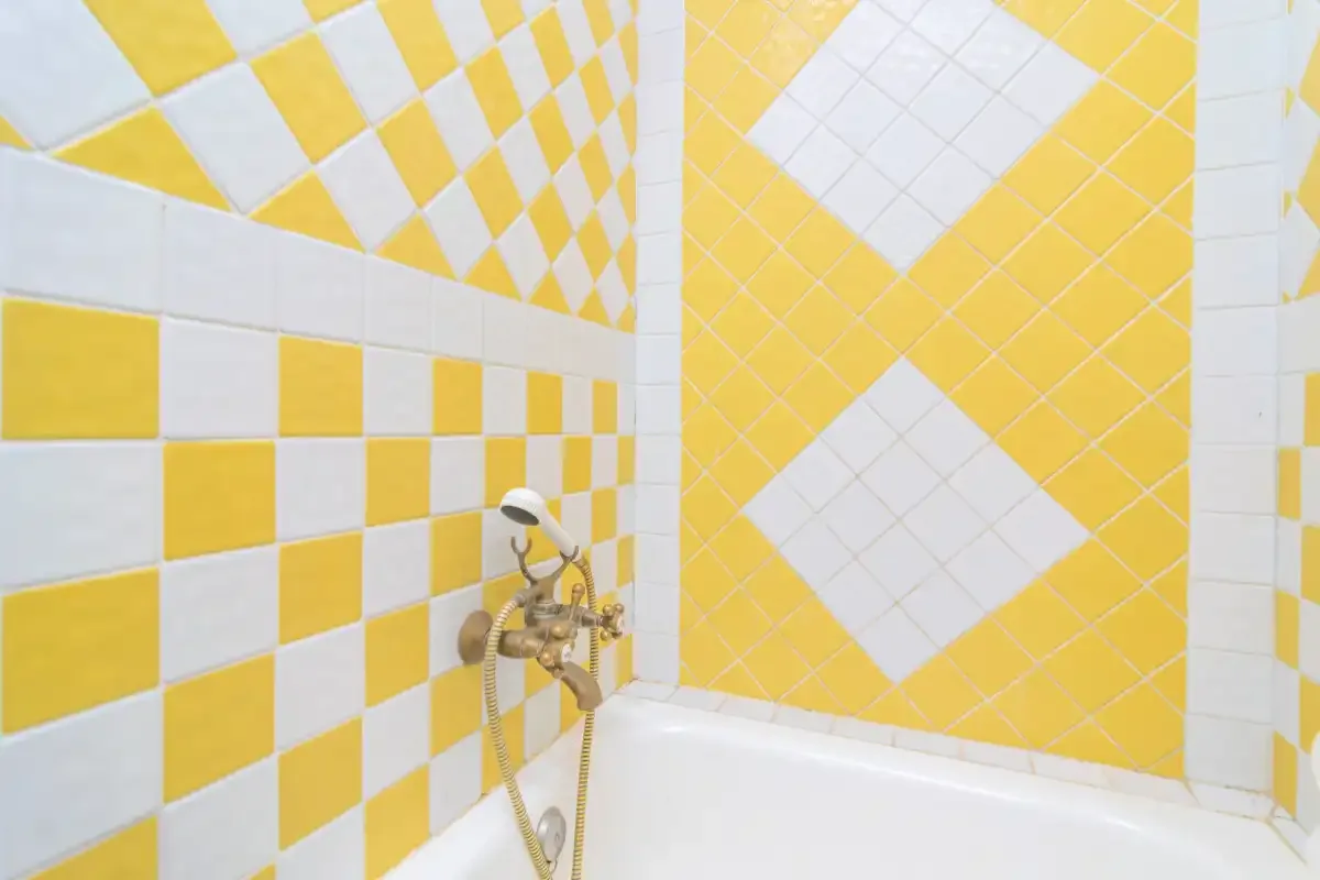 A tiled bathroom with a bathtub and wall-mounted shower fixture.