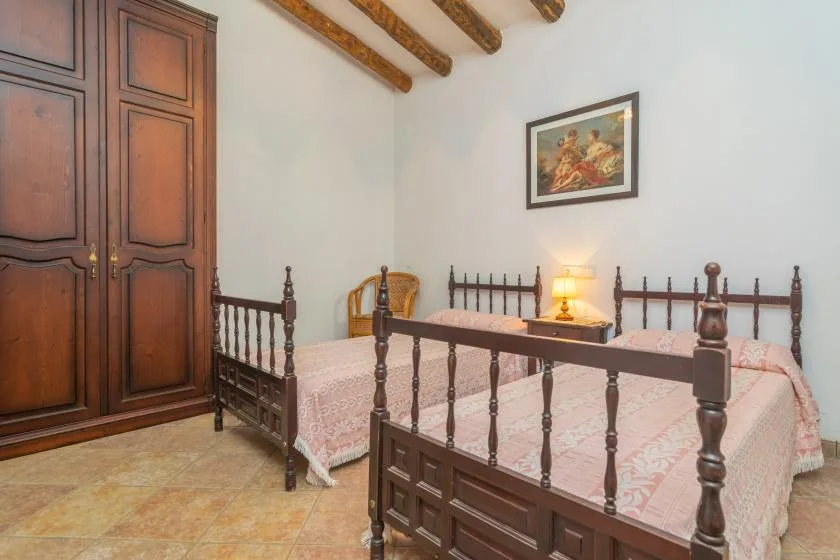 A bedroom with two beds, dark wooden furniture, and exposed ceiling beams.