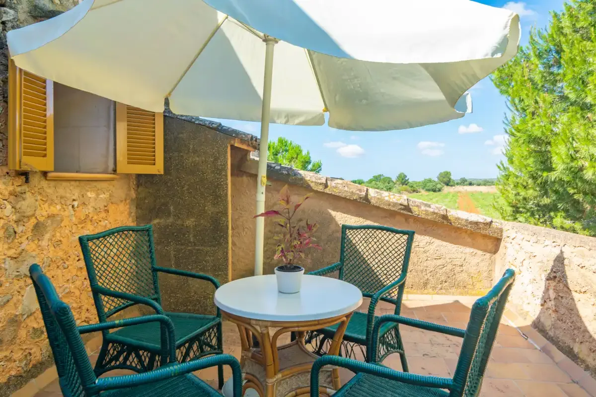 An outdoor patio with seating and a large umbrella beside a stone wall.