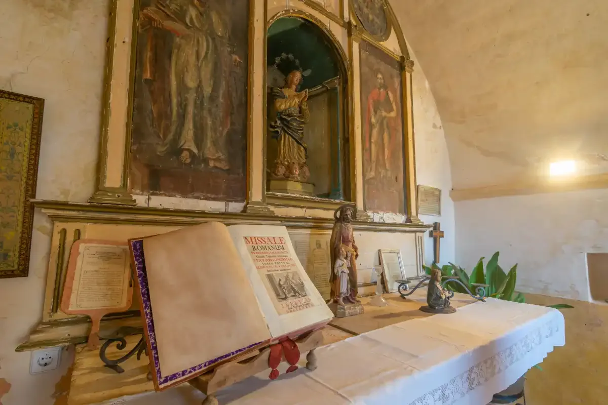 A chapel altar displays an open book beneath religious artwork.