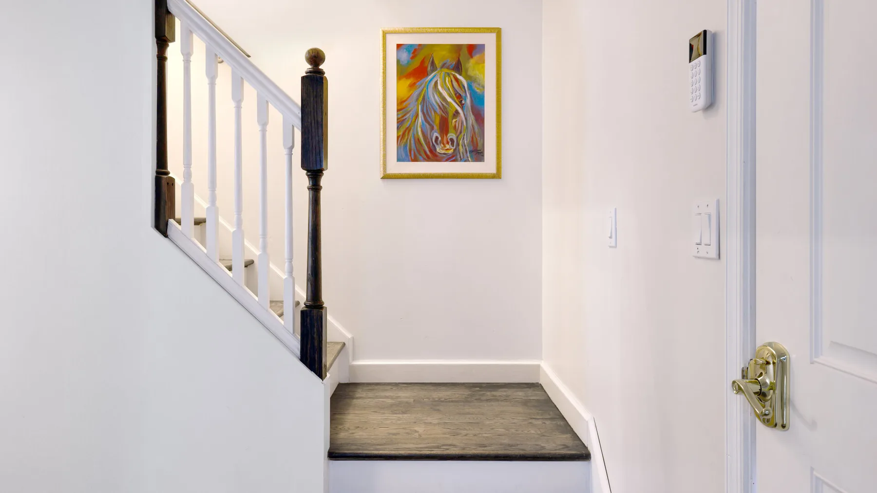 A stairway landing with framed artwork and a closed door.