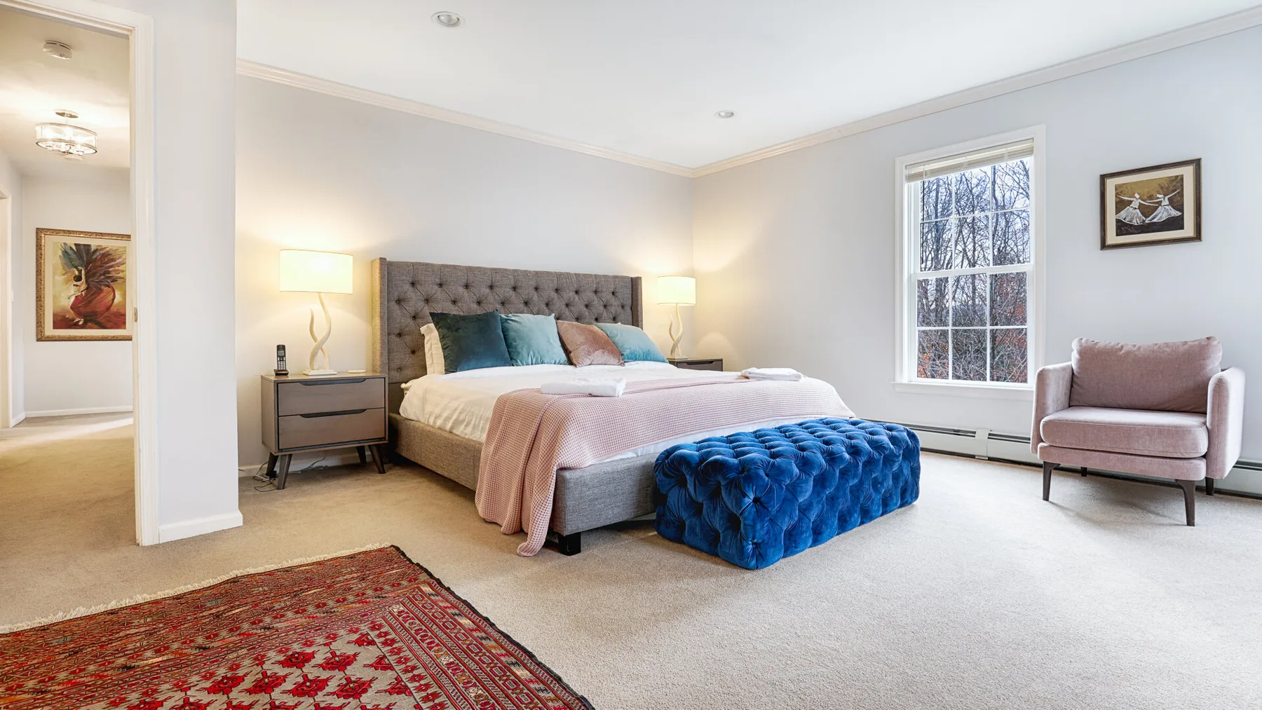 A bright bedroom with a large bed, bedside tables, and a window.