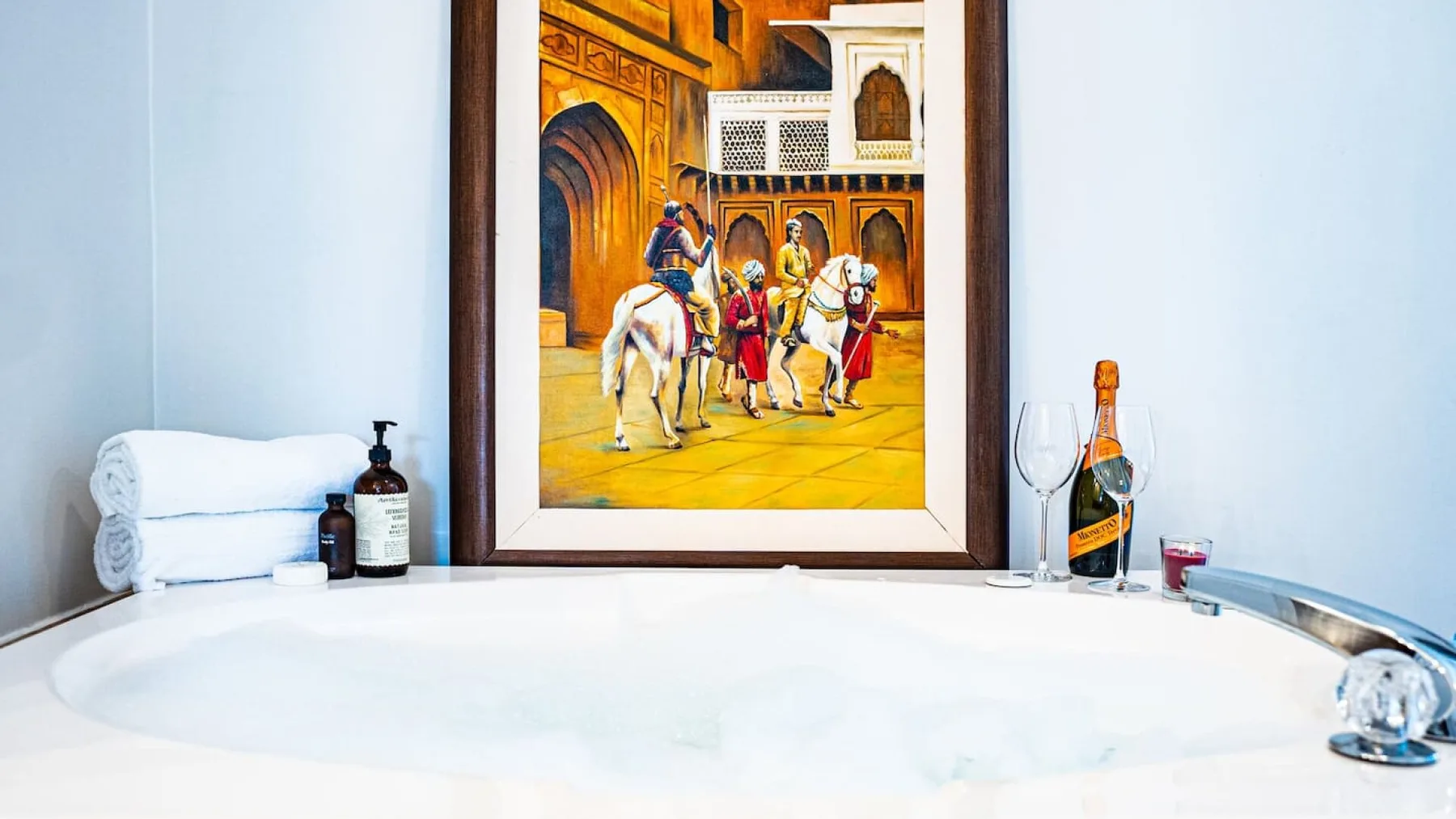 A bathroom with a large soaking tub and framed artwork above it.
