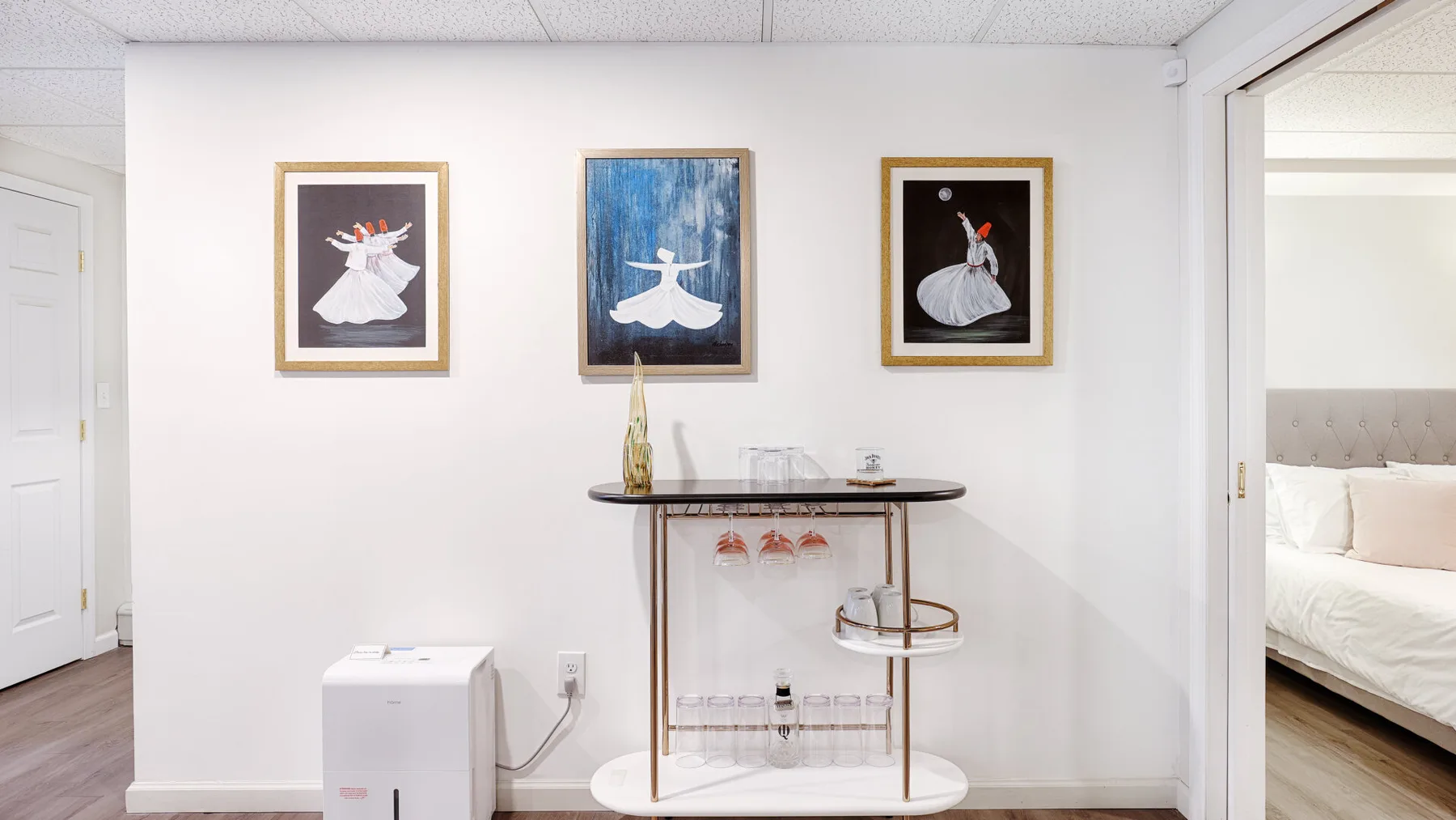 A bedroom sitting area has a narrow table beneath three framed ballet prints.