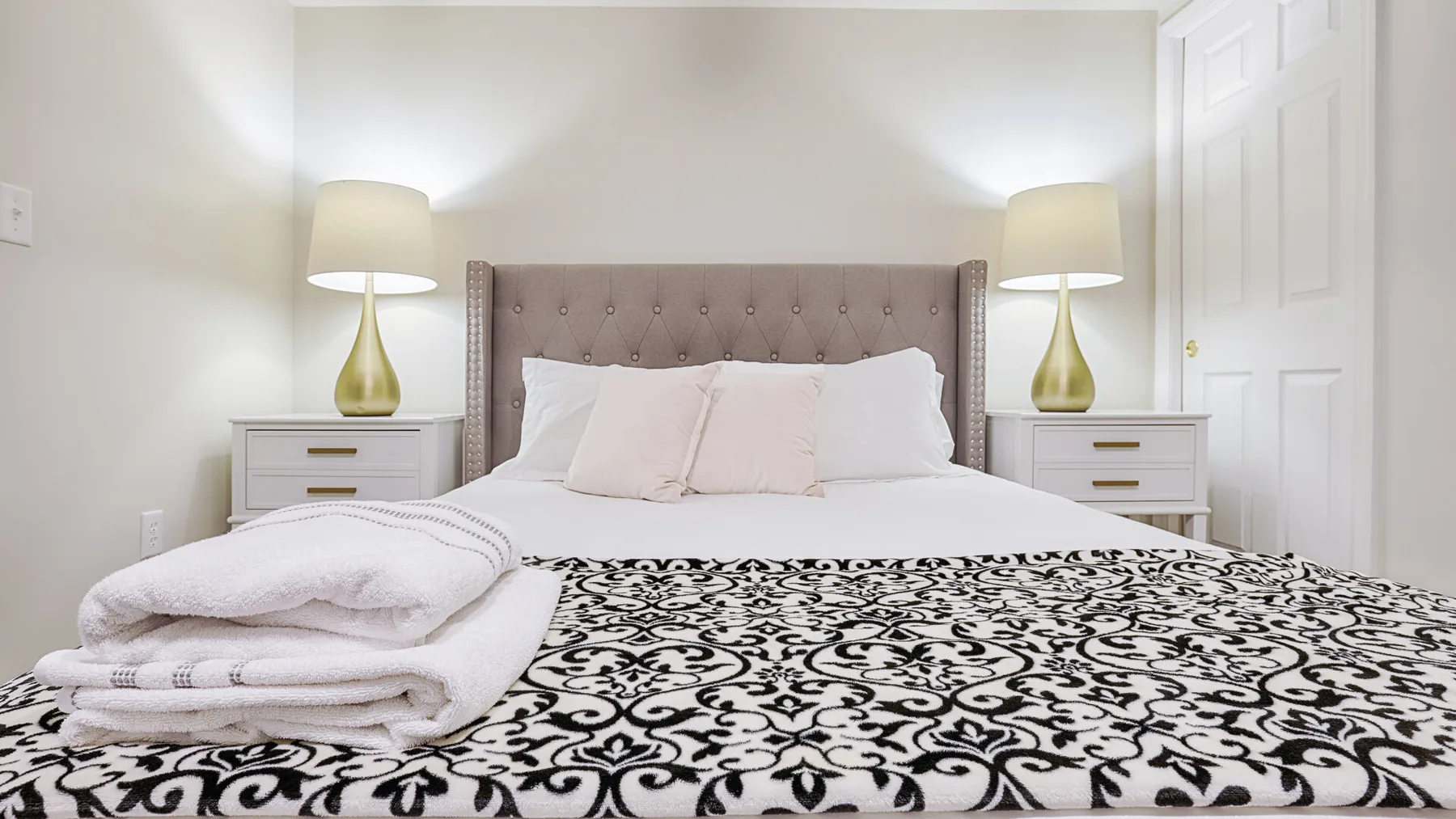 A bedroom with a neatly made bed and matching bedside lamps.