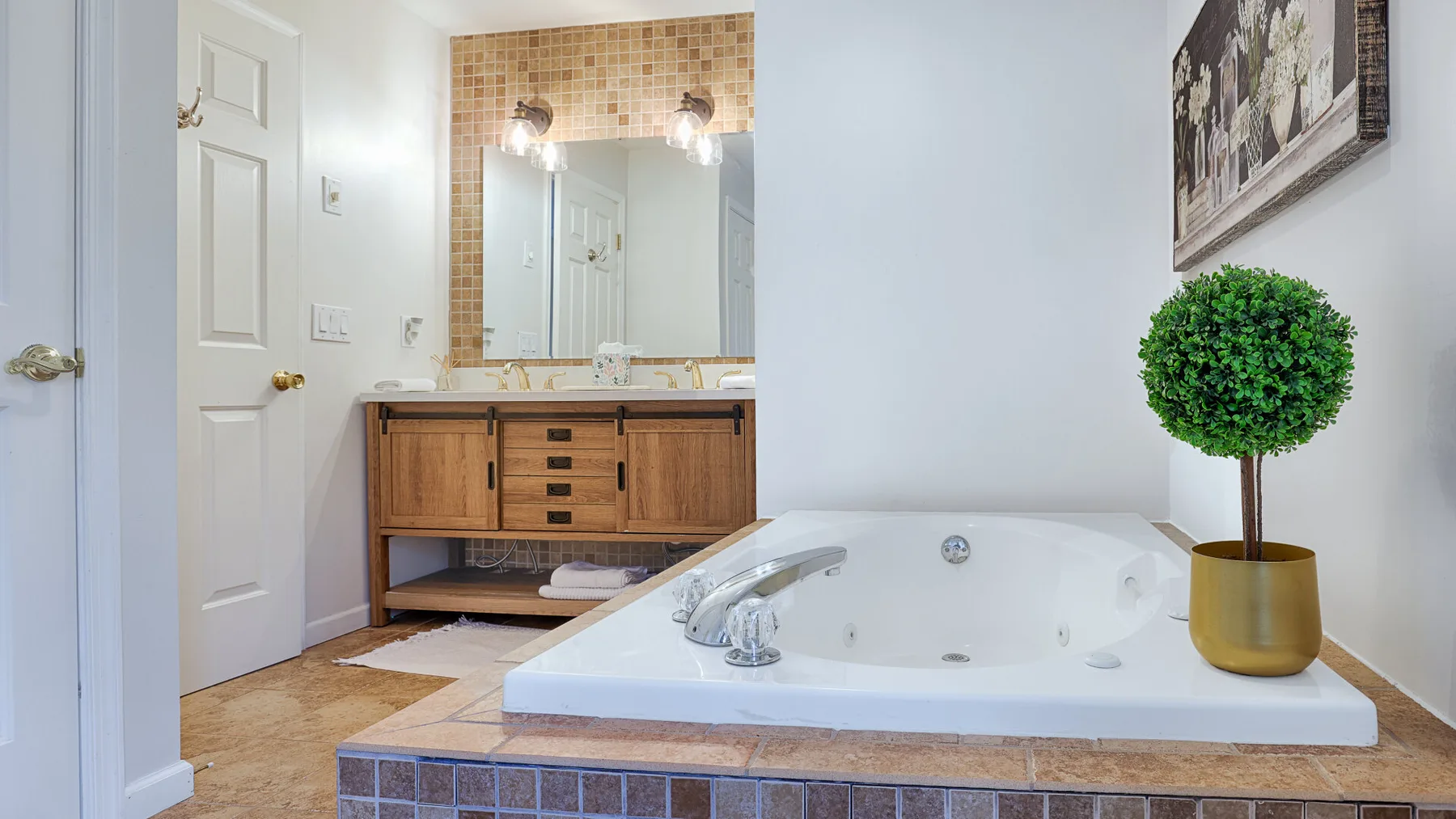 A bathroom with a built-in soaking tub, wooden vanity, and large mirror.
