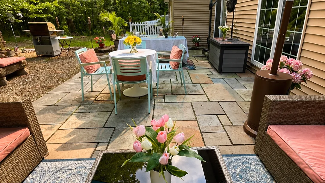 A paved outdoor patio with a dining table and garden seating.