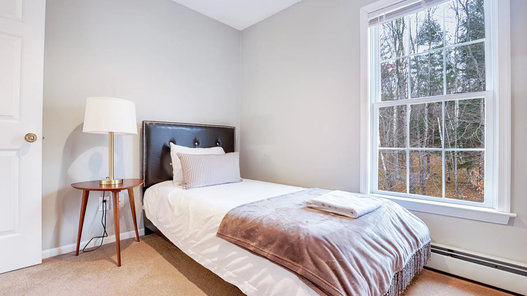 A bedroom with a bed beside a large window.
