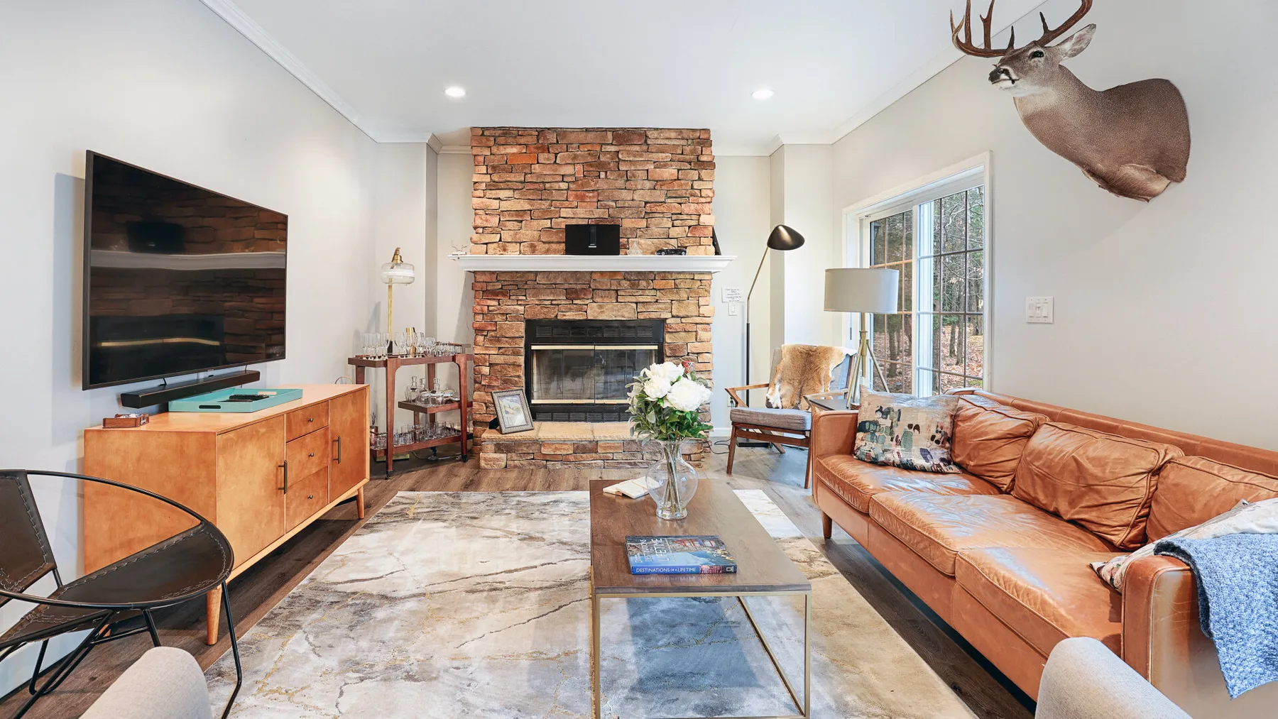 A bright living room with a brick fireplace and leather seating.