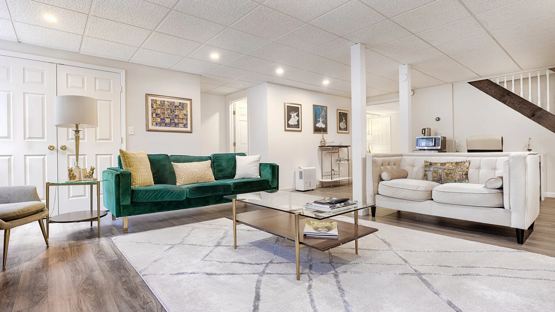 A bright living room with green and white seating around a glass coffee table.