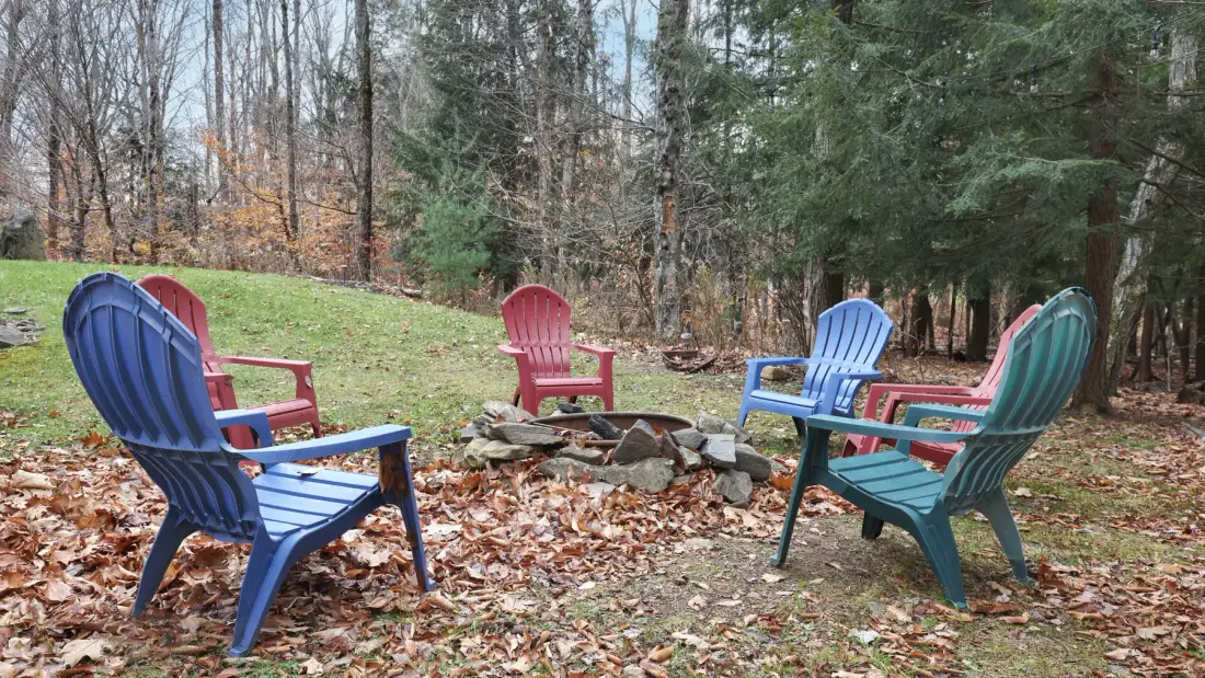 Outdoor seating area with colorful chairs arranged around a stone fire pit.