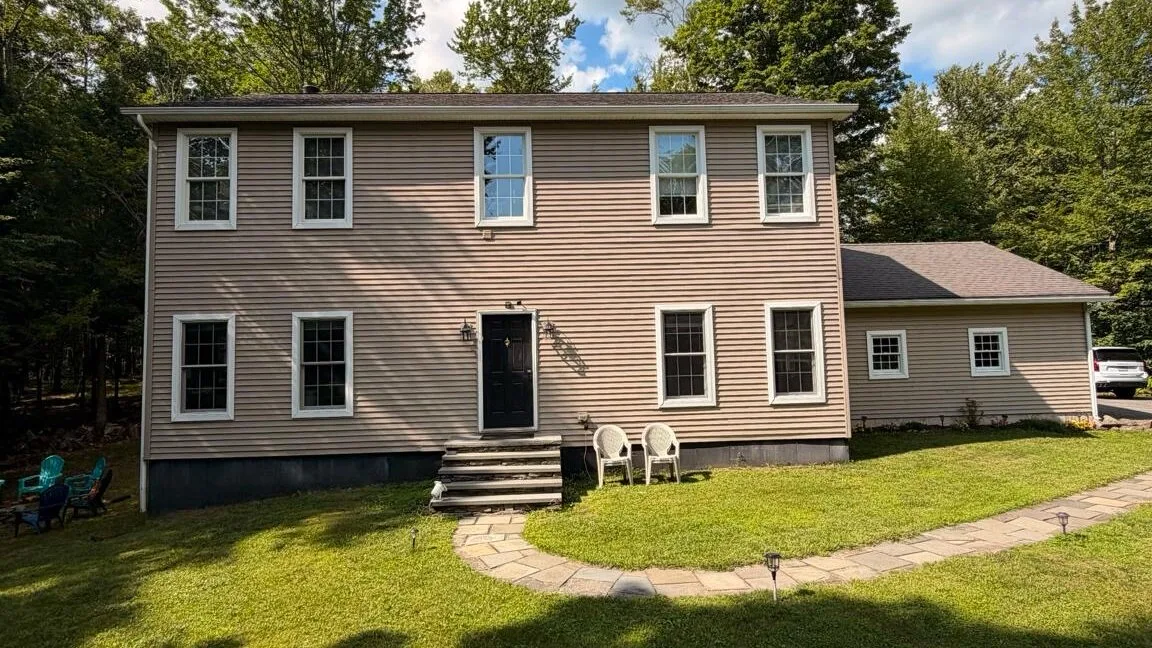 A two-story house with a small lawn and a curved stone walkway.