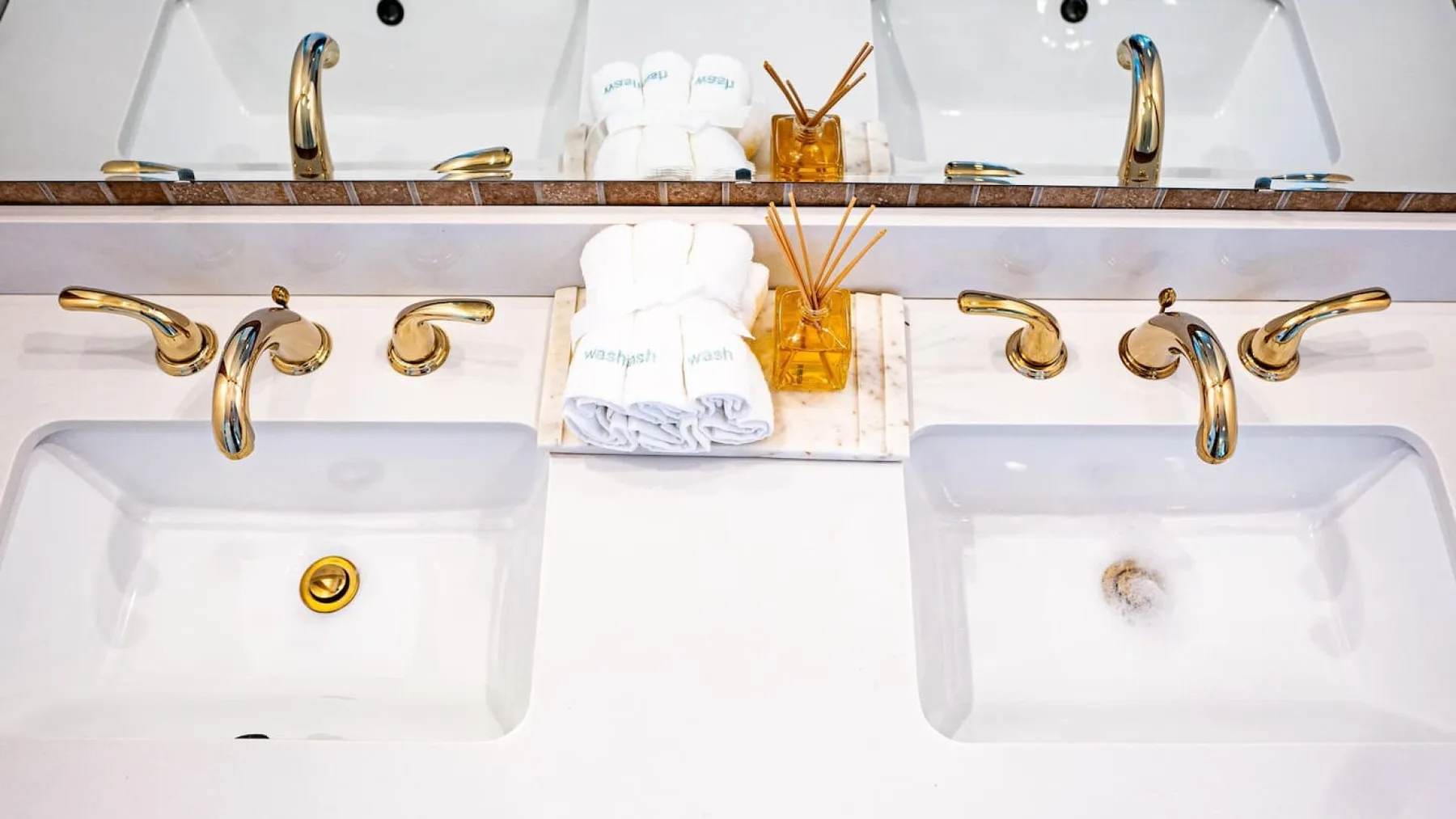 A bathroom vanity with two sinks and folded white towels.