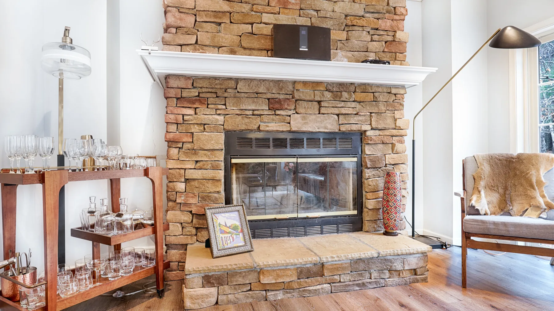 A stone fireplace anchors a bright living room with a glass-front firebox.