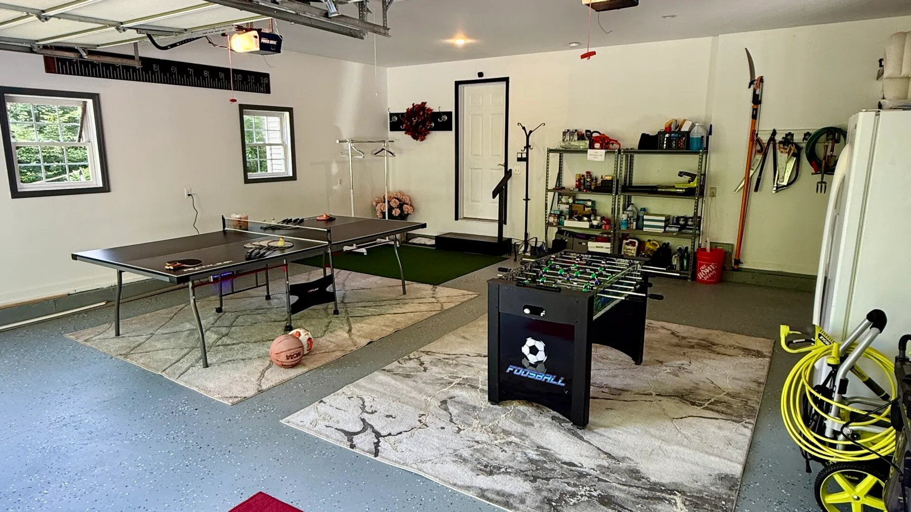 A garage game room with a foosball table and a ping-pong table.