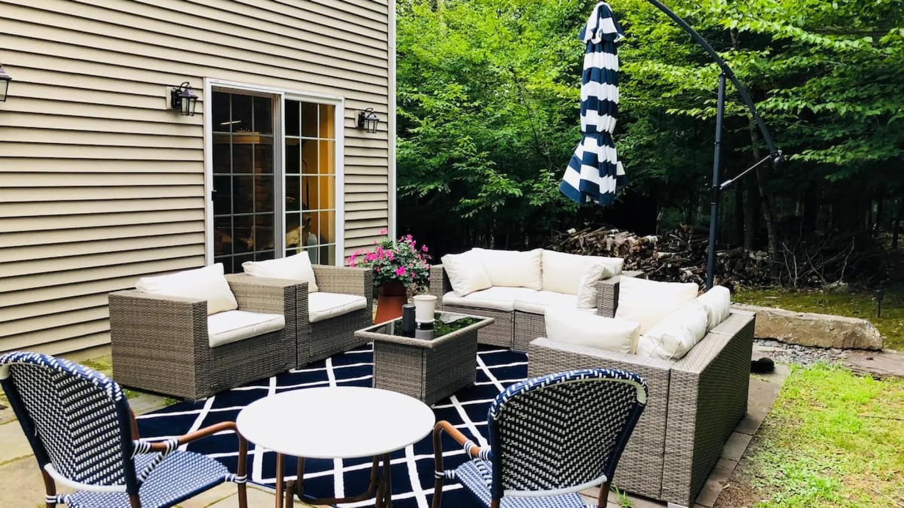 An outdoor patio with cushioned seating and a round table beside a house.