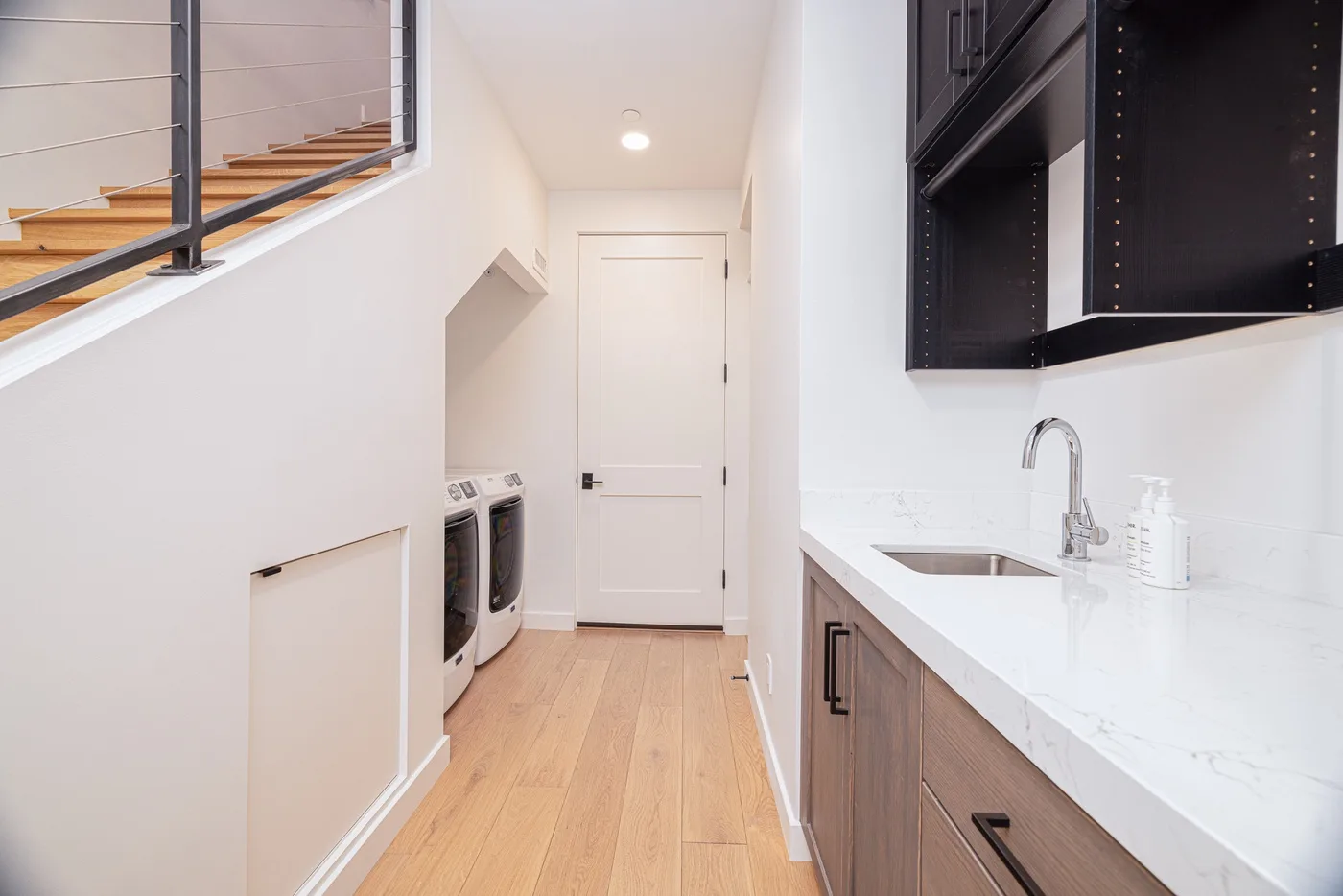 A bright laundry room with a washer and dryer beside a counter and sink.