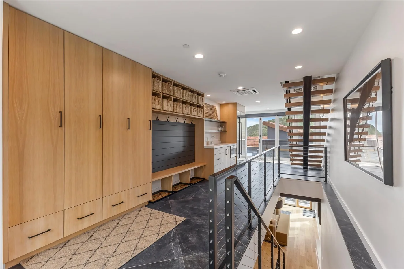 A modern interior hallway with wooden cabinetry and a glass railing.