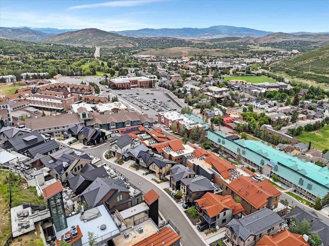 An aerial view shows a neighborhood of homes and buildings among rolling hills.
