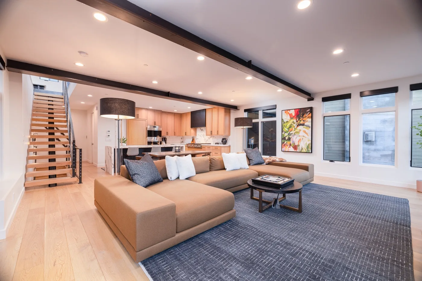 Open-plan living room with sectional seating, a coffee table, and kitchen beyond.